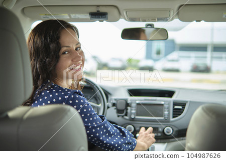 Young stylish woman driver sitting behind steering wheel of her car. Driving vehicle concept 104987626