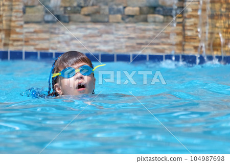 Young child girl in goggles exercises swimming in blue pool water. Summer recreation activity concept 104987698