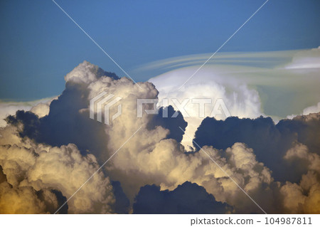 White fluffy cumulonimbus clouds forming before thunderstorm on evening sky. Changing stormy cloudscape weather at sunset White fluffy cumulonimbus clouds forming before thunderstorm on evening sky. Changing stormy cloudscape weather at sunset 104987811