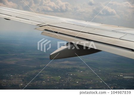 View of jet airplane wing landing at airport in bad weather. Travel and air transportation concept. 104987839