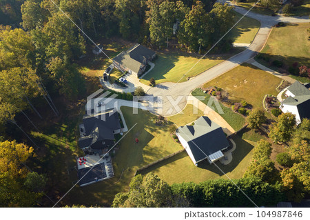 View from above of expensive residential houses between yellow fall trees in suburban area in South Carolina. American dream homes as example of real estate development in US suburbs View from above of expensive residential houses between yellow fall trees in suburban area in South Carolina. American dream homes as example of real estate development in US suburbs 104987846