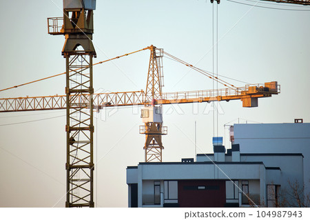 Tower cranes at high residential apartment buildings construction site. Real estate development Tower cranes at high residential apartment buildings construction site. Real estate development 104987943