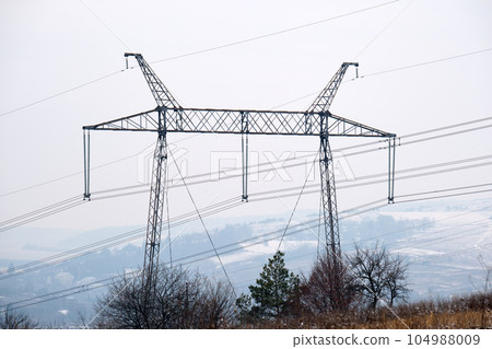 Steel pillar with high voltage electric power lines delivering electrical energy through cable wires on long distance Steel pillar with high voltage electric power lines delivering electrical energy through cable wires on long distance 104988009