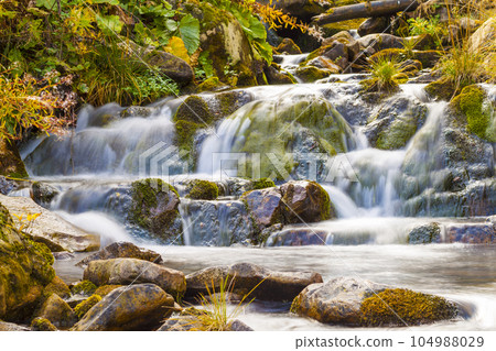 Small Waterfall in park with beautifull smooth water. Little waterfall in mountain forest with silky foaming water. Small Waterfall in park with beautifull smooth water. Little waterfall in mountain forest with silky foaming water. 104988029