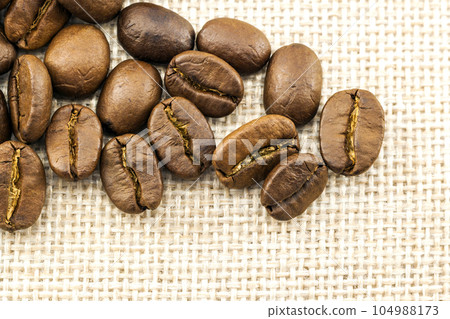 Roasted coffee beans on burlap sackcloth texture background 104988173