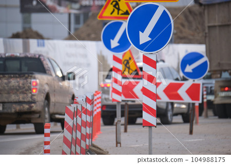 Roadworks warning traffic signs of construction work on city street and slowly moving cars 104988175