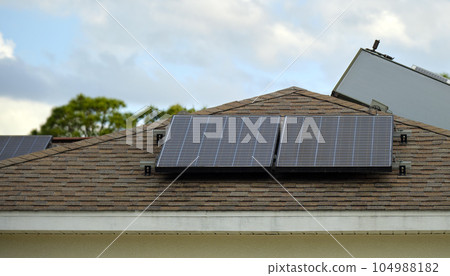 Residential house with rooftop covered with solar photovoltaic panels for producing of clean ecological electrical energy in suburban rural area. Concept of autonomous home Residential house with rooftop covered with solar photovoltaic panels for producing of clean ecological electrical energy in suburban rural area. Concept of autonomous home 104988182
