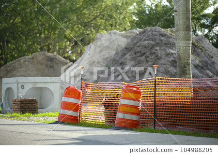 Protective restriction barrier at industrial construction site. Safety mesh fence for pedestrians Protective restriction barrier at industrial construction site. Safety mesh fence for pedestrians 104988205