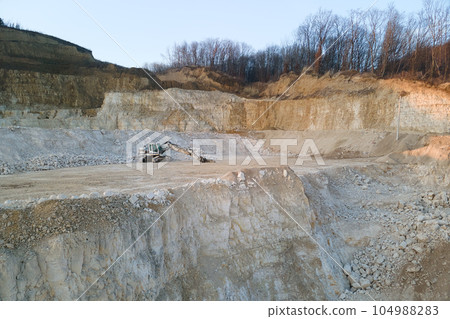 Open pit mining site of construction sand stone materials with excavator equipment for digging of gravel resources at quarry 104988283