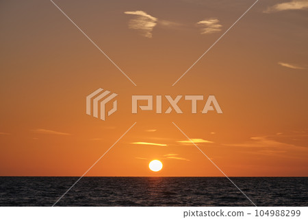 Ocean sunset. Big white sun on dramatic bright sky background, soft evening cloud over sea dark water Ocean sunset. Big white sun on dramatic bright sky background, soft evening cloud over sea dark water 104988299