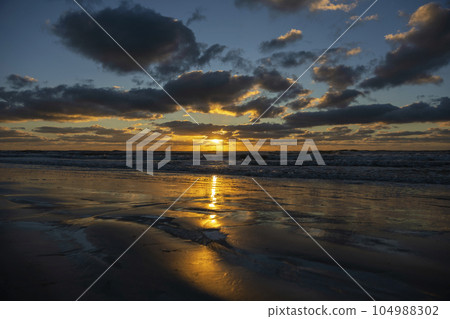 Ocean sunset landscape with soft evening sea water waves crushing on sandy beach 104988302