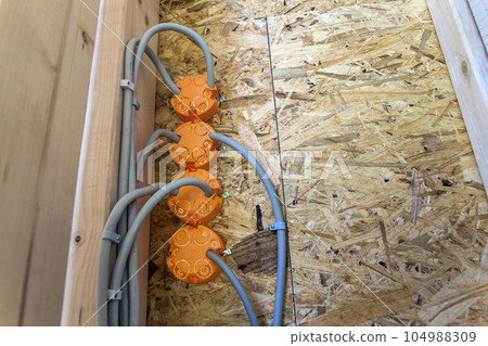New electrical installation, socket plastic boxes and electrical cables on the wall, renovation concept. Electrical wiring installation. New electrical installation, socket plastic boxes and electrical cables on the wall, renovation concept. Electrical wiring installation. 104988309