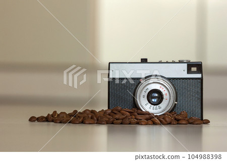 Little old fashioned vintage camera and coffee beanes on blurred background Little old fashioned vintage camera and coffee beanes on blurred background 104988398