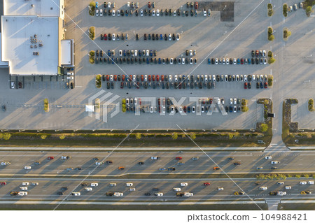 Large parking lot of local dealer with many brand new cars parked for sale on highway roadside. Development of american automotive industry and distribution of manufactured vehicles concept Large parking lot of local dealer with many brand new cars parked for sale on highway roadside. Development of american automotive industry and distribution of manufactured vehicles concept 104988421