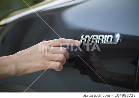 Human hand showing hybrid car sign on new effective vehicle Human hand showing hybrid car sign on new effective vehicle 104988722
