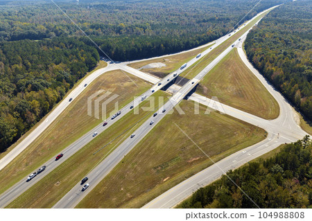 Elevated view of freeway exit junction over road lanes with fast moving traffic cars and trucks. Interstate transportation infrastructure in USA Elevated view of freeway exit junction over road lanes with fast moving traffic cars and trucks. Interstate transportation infrastructure in USA 104988808