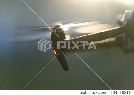 Drone aircraft with blurred fast rotating propellers and video camera flying in air Drone aircraft with blurred fast rotating propellers and video camera flying in air 104988816