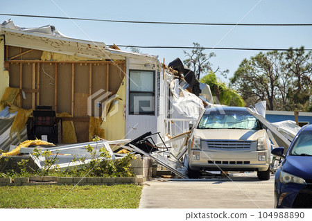 Destroyed by hurricane Ian suburban house and damaged car in Florida mobile home residential area. Consequences of natural disaster 104988890