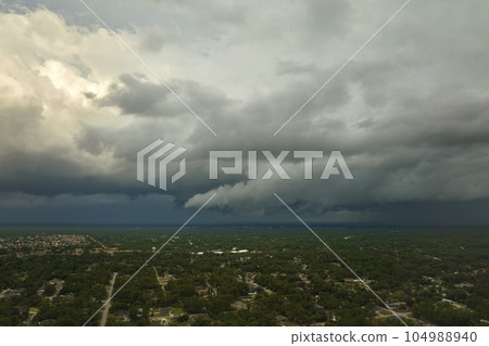 Dark stormy clouds forming on gloomy sky before heavy rainfall over suburban town area Dark stormy clouds forming on gloomy sky before heavy rainfall over suburban town area 104988940