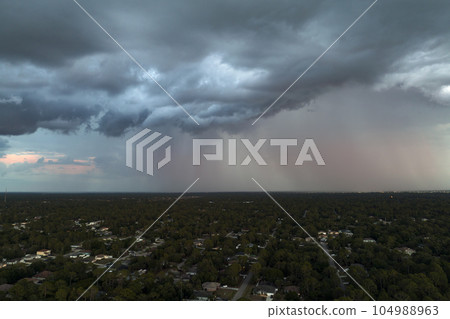 Dark stormy clouds forming on gloomy sky before heavy rainfall over suburban town area Dark stormy clouds forming on gloomy sky before heavy rainfall over suburban town area 104988963