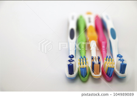 Colorful toothbrushes on white background with copy space. Macro with shallow dof. 104989089