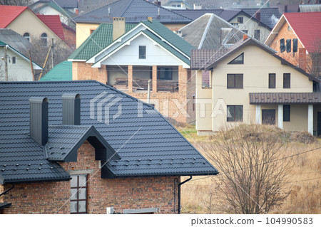 Chimney on house roof top covered with metallic shingles under construction. Tiled covering of building. Real estate development 104990583