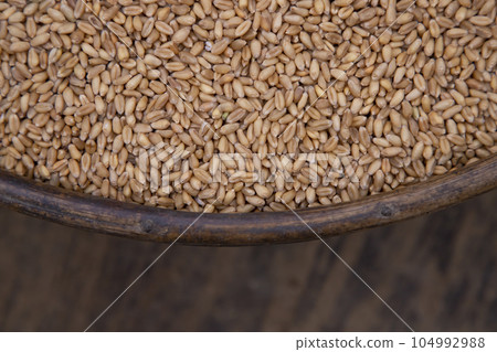 Wheat grains in a bowl on a wooden background, top view Wheat grains in a bowl on a wooden background, top view 104992988