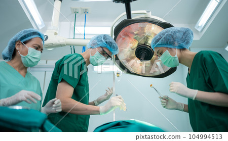 Asian Professional surgeons team performing surgery in the operating room, surgeon, Assistants, and Nurses Performing Surgery on a Patient, health care cancer and disease treatment concept Asian Professional surgeons team performing surgery in the operating room, surgeon, Assistants, and Nurses Performing Surgery on a Patient, health care cancer and disease treatment concept 104994513