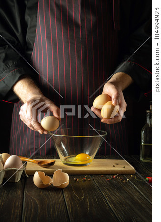 The chef prepares an egg omelette for breakfast. Working environment in a restaurant kitchen. Copy space The chef prepares an egg omelette for breakfast. Working environment in a restaurant kitchen. Copy space 104994923