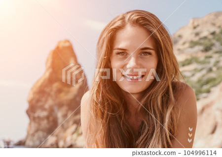 Woman summer travel sea. Happy tourist enjoy taking picture outdoors for memories. Woman traveler posing on the beach at sea surrounded by volcanic mountains, sharing travel adventure journey Woman summer travel sea. Happy tourist enjoy taking picture outdoors for memories. Woman traveler posing on the beach at sea surrounded by volcanic mountains, sharing travel adventure journey 104996114