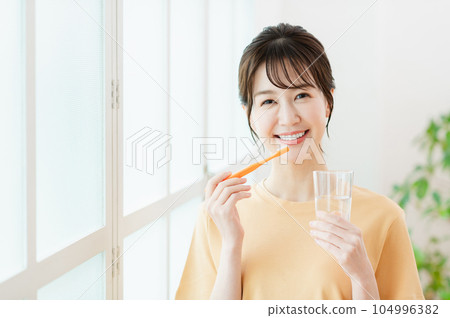 A young woman brushing a tooth 104996382
