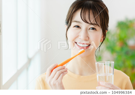 A young woman brushing a tooth A young woman brushing a tooth 104996384