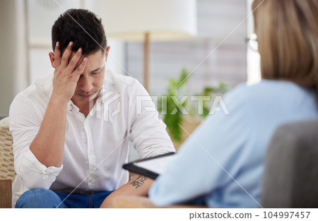 It consumes me. a handsome young man sitting in the clinic with his therapist and feeling stressed. 104997457