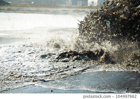 Pollution, sewer and waste in water to ocean from industrial for construction, pipeline and danger. Environment, texture and industry with wave from sewage on shoreline for stream, foam and mud 104997662