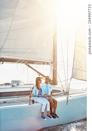 Couple, boat and adventure at sea for holiday during summer to relax on luxury or rich cruise. Ocean, vacation and people on yacht for outdoor travel and freedom to enjoy the sunshine together. 104997733
