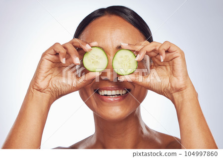 Cucumber, face and beauty of woman in studio, white background and aesthetic glow. Happy female model, natural skincare and fruits on eyes for sustainable cosmetics, vegan dermatology and nutrition Cucumber, face and beauty of woman in studio, white background and aesthetic glow. Happy female model, natural skincare and fruits on eyes for sustainable cosmetics, vegan dermatology and nutrition 104997860
