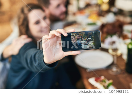 Couple, family lunch and phone selfie in home at dinner table for thanksgiving celebration memory. Festive fine dining, love and man and woman take picture with mobile smartphone for social media. Couple, family lunch and phone selfie in home at dinner table for thanksgiving celebration memory. Festive fine dining, love and man and woman take picture with mobile smartphone for social media. 104998151