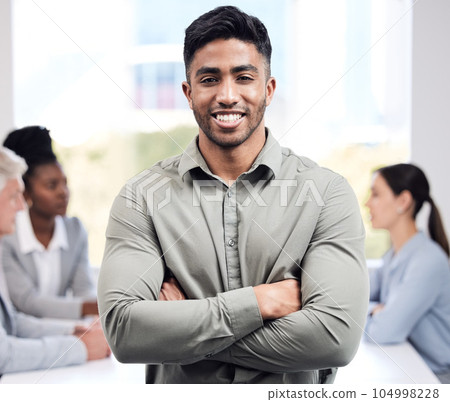Portrait, smile and a business man arms crossed in the boardroom with his team planning in the background. Leadership, workshop and confidence with a happy young male employee standing in the office Portrait, smile and a business man arms crossed in the boardroom with his team planning in the background. Leadership, workshop and confidence with a happy young male employee standing in the office 104998228