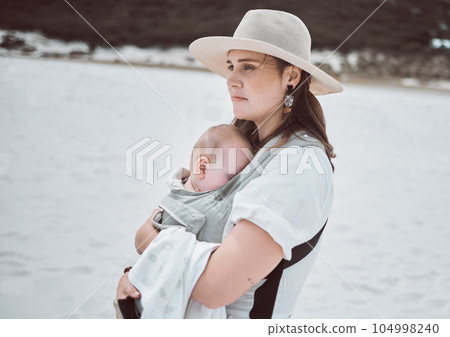 Find a break at the beach. Shot of a young mother holding her baby while at the beach. Find a break at the beach. Shot of a young mother holding her baby while at the beach. 104998240