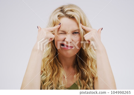 Portrait, funny face and fingers on head with a woman in studio on a gray background looking silly or goofy. Comedy, comic and mental with a crazy young female person joking for fun or playful humor 104998265