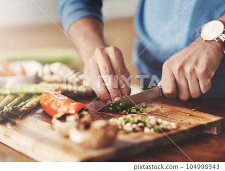 Cooking, chopping board and hands of man in kitchen for food, wellness and nutrition. Health, diet and dinner with closeup of male chef cutting vegetables with knife at home for lunch, vegan or salad Cooking, chopping board and hands of man in kitchen for food, wellness and nutrition. Health, diet and dinner with closeup of male chef cutting vegetables with knife at home for lunch, vegan or salad 104998343