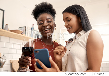 Appreciate these moments while you can. Shot of two young friends using a phone while spending time together at home. 104998445