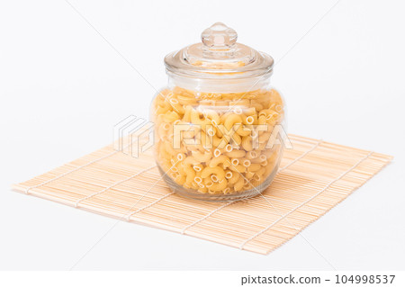Uncooked Chifferi Rigati Pasta in Glass Jar on Bamboo Mat Isolated 104998537
