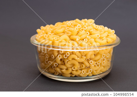 Uncooked Chifferi Rigati Pasta in Glass Jar on Black Background 104998554