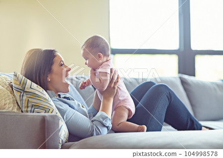 Woman, bonding and laughing mother with baby girl on house living room, relax nursery and family home sofa. Smile, happy and infant child with mom in comic, funny or silly children game in trust love Woman, bonding and laughing mother with baby girl on house living room, relax nursery and family home sofa. Smile, happy and infant child with mom in comic, funny or silly children game in trust love 104998578
