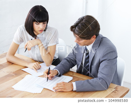 Business people, documents and writing in meeting for planning, marketing or strategy on office desk. Businessman and woman in teamwork collaboration with paperwork for project plan at the workplace 104998580