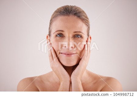 Portrait, senior woman and face for cosmetic wellness or touching her perfect skin or isolated and on grey background. Mature lady, massaging wrinkles and facial aging or dermatology and skincare 104998712