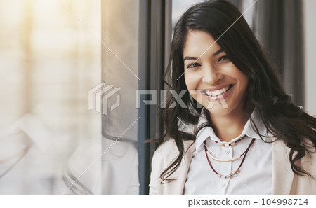 Business woman, portrait smile and window for corporate management, leadership or success at office. Happy and friendly young female leader or manager smiling for career goals, ambition or startup Business woman, portrait smile and window for corporate management, leadership or success at office. Happy and friendly young female leader or manager smiling for career goals, ambition or startup 104998714