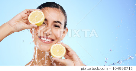 Beauty, lemon and water splash with portrait of woman in studio for natural cosmetics, nutrition and mockup. Glow, fruits and hydration with female on blue background for vitamin c, face and skincare Beauty, lemon and water splash with portrait of woman in studio for natural cosmetics, nutrition and mockup. Glow, fruits and hydration with female on blue background for vitamin c, face and skincare 104998715