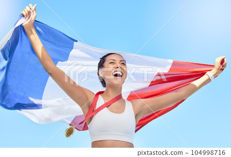 French athlete celebrating her gold medal olympic win, flying a flag. Smiling fit active sporty woman feeling motivated. Celebrating national pride and achieving gold medal in olympic sport 104998716